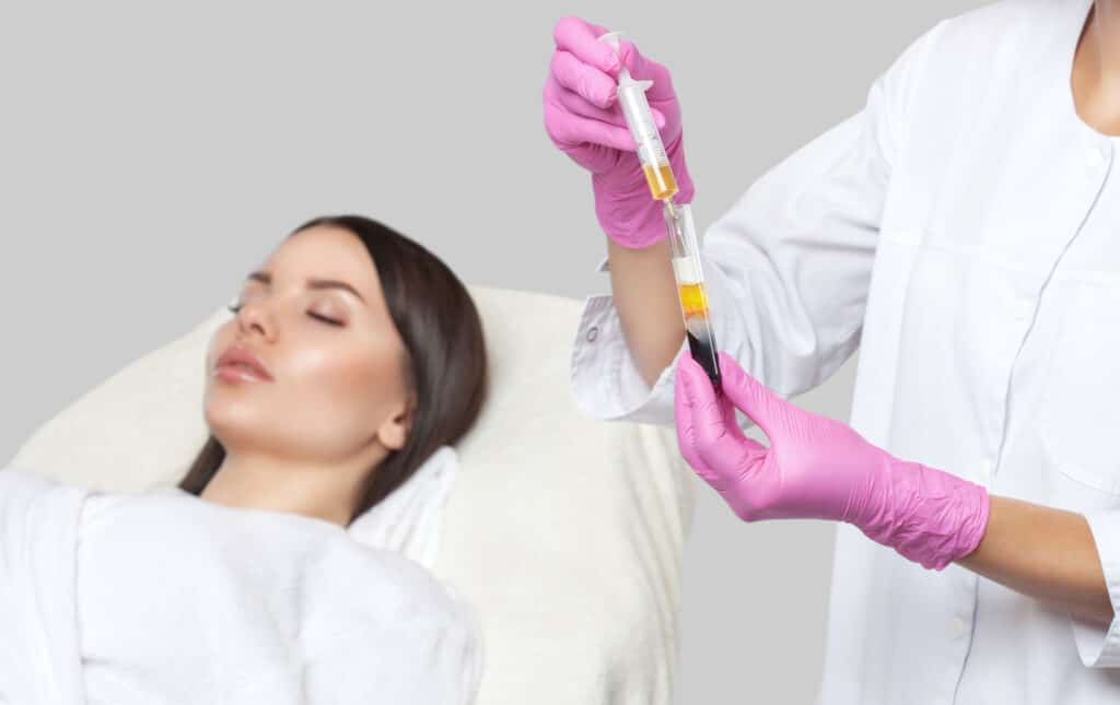 Cosmetologist does prp therapy on the face of a beautiful woman in a beauty salon. There is in vitro blood plasma, ready for injection. Cosmetology concept.